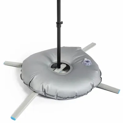 A weighted base for flagpoles or banners rests on a white surface, featuring a circular shape with several metal spokes protruding from its center.